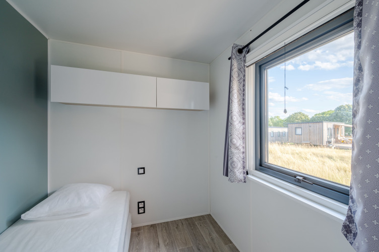 Dormitorio moderno con cama individual, ventana grande y armario blanco en Cottage Prestige en Francia.