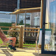 En person slapper af i en liggestol på træterrassen ved Cottage Prestige lodge på en solrig dag.