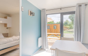 Bright interior of Cottage Prestige at Camping Seasonova Les Portes d'Alsace with terrace view in France.