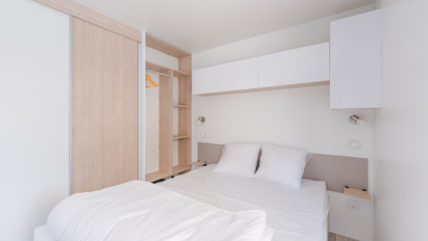 Habitación moderna y minimalista en Cottage Prestige con cama doble, ropa blanca y armario en Camping Seasonova.