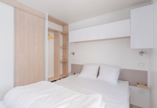 Habitación moderna y minimalista en Cottage Prestige con cama doble, ropa blanca y armario en Camping Seasonova.