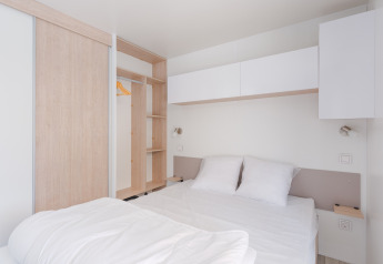 Moderne, minimalistisk soveværelse med dobbeltseng, hvidt sengetøj og indbygget skab på Cottage Prestige.