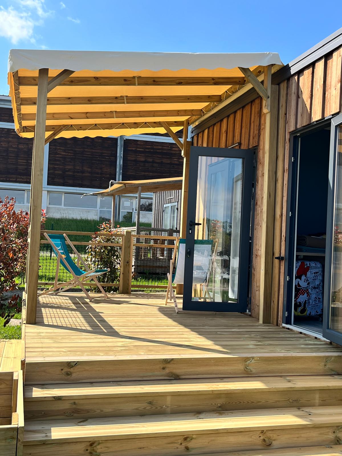 Zonnig houten terras met ligstoelen bij Cottage Prestige, Camping Seasonova Les Portes d'Alsace, Frankrijk