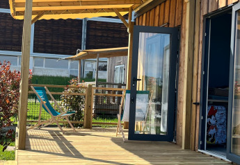 Terraza soleada de madera con sillas en Cottage Prestige, Camping Seasonova Les Portes d'Alsace, Francia