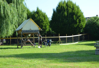Una tienda safari Bivouac y bicicletas en Camping Seasonova Les Portes d'Alsace, Francia, sobre césped verde.