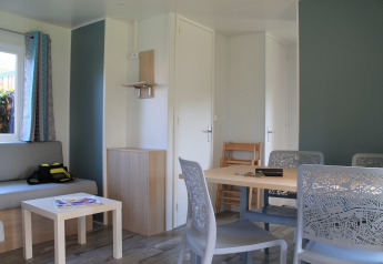 Moderne opholdsstue i Cottage Prestige på Camping Seasonova Etennemare, med sofabænk og spisebord.