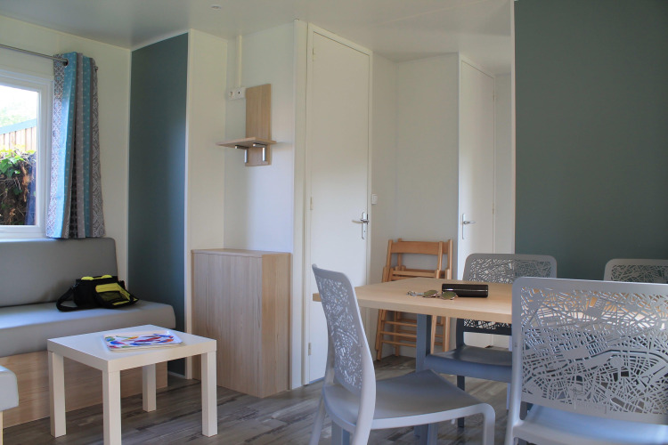 Bright living area inside Cottage Prestige at Camping Seasonova Etennemare, France, with sofa and table.
