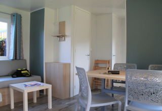 Helles Wohnzimmer im Cottage Prestige, Camping Seasonova Etennemare, mit Esstisch und Sofa zu sehen.