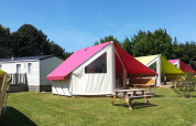 Colorful safari tents and mobile homes at Camping Seasonova Etennemare in France on a sunny day.