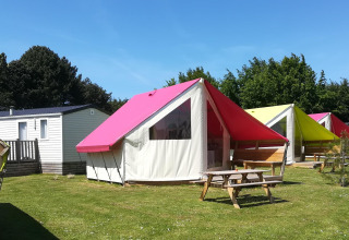 Foto af farverige safari-telte og mobile homes på Camping Seasonova Etennemare, Frankrig, under blå himmel.