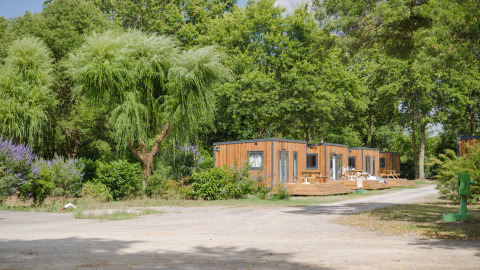 Houten chalets tussen bomen in Camping Seasonova du Chêne, een vakantiepark in Pays de la Loire, Frankrijk.