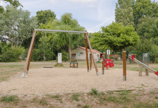 Legeplads med gynger, vippe og legeredskaber i naturmiljø ved Camping Seasonova du Chêne i Pays de la Loire.