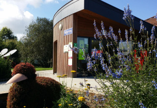 Receptionen på Camping Seasonova du Chêne i Pays de la Loire, Frankrig, omgivet af blomster og en buskdyrfigur.