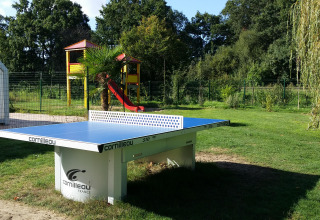 Udendørs bordtennisbord ved Camping Seasonova du Chêne, med legeplads i baggrunden i Pays de la Loire.