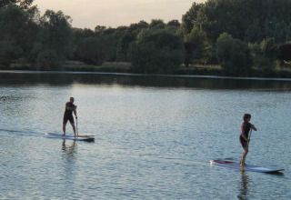 Due persone fanno paddleboard su un lago tranquillo al Camping Seasonova du Chêne in Pays de la Loire, Francia.