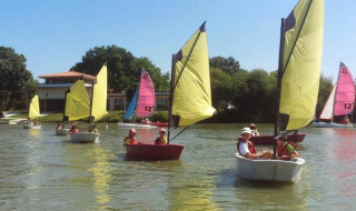Kinder segeln mit bunten Booten auf einem See bei Saint Julien de Concelles, Pays de la Loire, Frankreich.