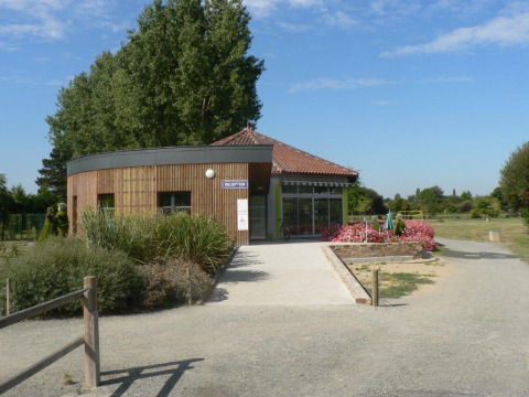Edificio de recepción en Camping Seasonova du Chêne, parque vacacional en Pays de la Loire, Francia, rodeado de flores.