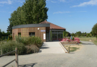 Receptionen ved Camping Seasonova du Chêne feriepark i Pays de la Loire, Frankrig, omgivet af blomster og grønt.