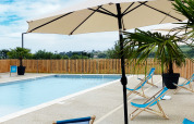 Außenpool mit blauen Liegestühlen, Sonnenschirmen und Palmen im Domaine Seasonova Saâne et Mer, Normandie, Frankreich.