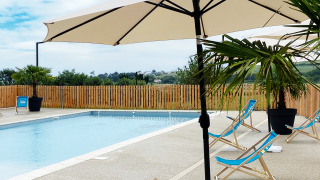 Piscine extérieure avec transats bleus, parasols et palmiers au Domaine Seasonova Saâne et Mer, Normandie, France.