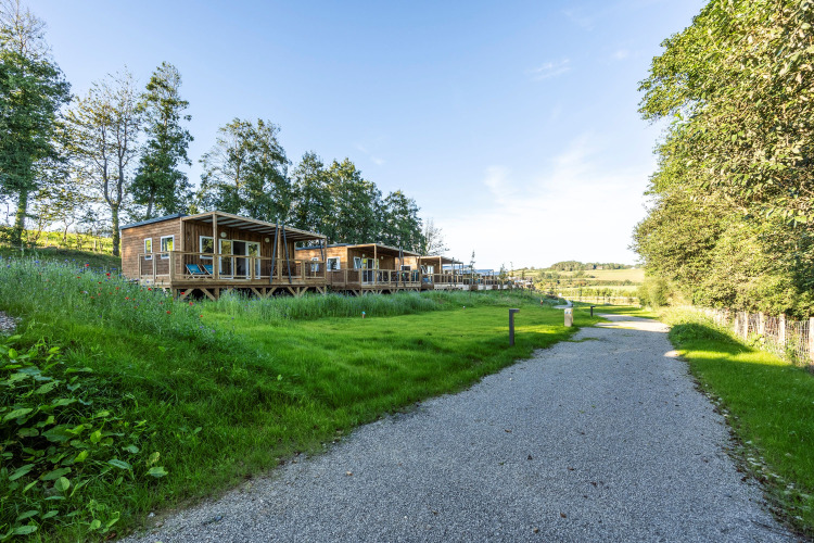 Wooden cabins at Domaine Seasonova Saâne et Mer holiday park surrounded by lush greenery in Normandy, France