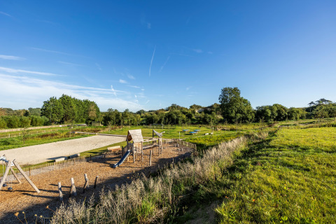 Spielplatz und weite Wiesen unter blauem Himmel im Domaine Seasonova Saâne et Mer Ferienpark in der Normandie, Frankreich.