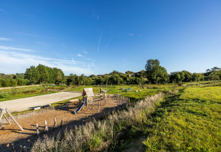 Parque infantil y campos verdes bajo un cielo despejado en Domaine Seasonova Saâne et Mer, Normandía, Francia.
