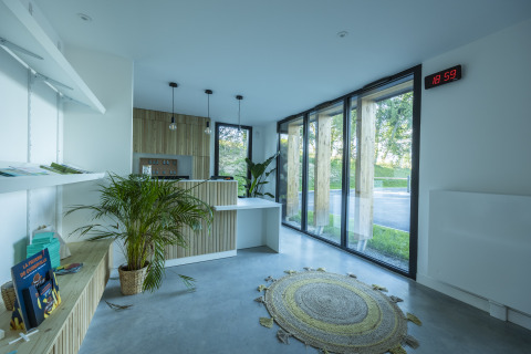 Recepción luminosa con plantas, grandes ventanales y muebles de madera en Domaine Seasonova Saâne et Mer, Normandía.