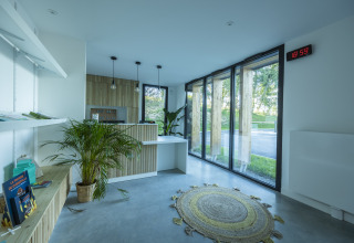 Recepción luminosa con plantas, grandes ventanales y muebles de madera en Domaine Seasonova Saâne et Mer, Normandía.