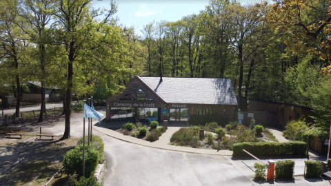 Toegang tot Camping Seasonova La Forêt in Pays de la Loire, Frankrijk, omringd door bomen en bos.
