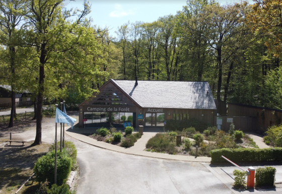 Ingang van Camping Seasonova La Forêt in Pays de la Loire, Frankrijk, omgeven door groene bomen en bos.