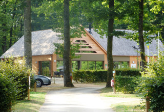 Indgang til Camping Seasonova La Forêt, et feriecenter omgivet af træer i Pays de la Loire, Frankrig.