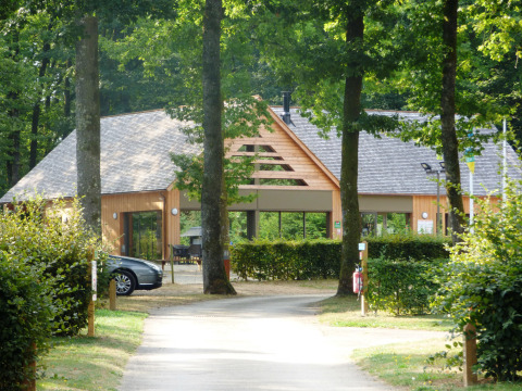 Indgang til Camping Seasonova La Forêt, et feriecenter omgivet af træer i Pays de la Loire, Frankrig.