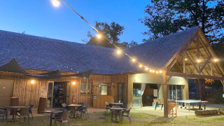 Vista serale al Camping Seasonova La Forêt in Pays de la Loire, Francia, con luci e tavoli all'aperto.