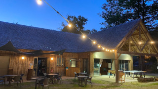 Vista nocturna en Camping Seasonova La Forêt en Pays de la Loire, Francia, con luces y zona de mesas al aire libre.