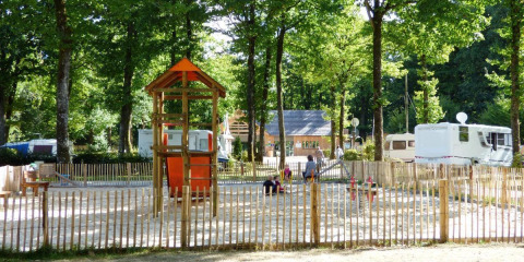 Speelterrein met toren en glijbaan bij Camping Seasonova La Forêt, Pays de la Loire, Frankrijk, omringd door bomen.