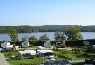 Panoramabillede af Camping Seasonova La Forêt med campingvogne ved en sø i Pays de la Loire, Frankrig.