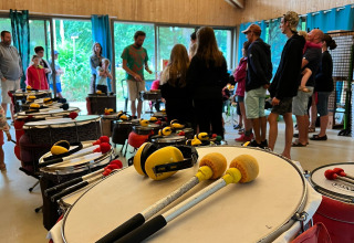 Folk samles til et trommeworkshop i et træhus på Camping Seasonova La Forêt i Pays de la Loire, Frankrig.