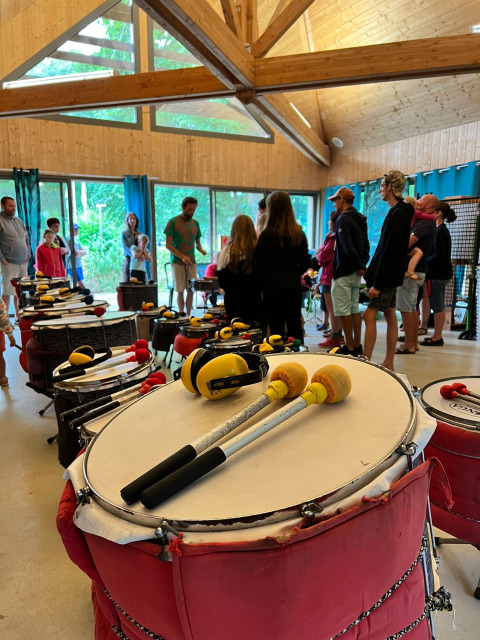 People enjoy a drumming workshop in a wooden hall at Camping Seasonova La Forêt, Pays de la Loire, France.