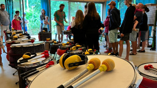 Personas disfrutan de un taller de percusión en una sala de madera en Camping Seasonova La Forêt, Pays de la Loire.