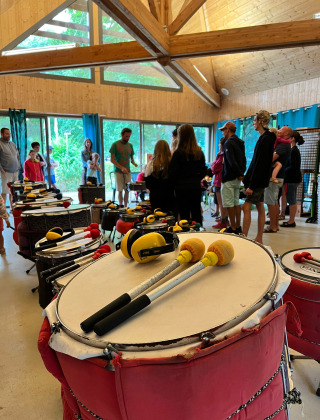 Personas disfrutan de un taller de percusión en una sala de madera en Camping Seasonova La Forêt, Pays de la Loire.