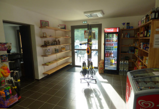 Interno negozio al Camping Seasonova La Forêt in Pays de la Loire, Francia, con scaffali e frigorifero.