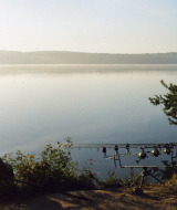Lago tranquilo en Sillé le Guillaume, Pays de la Loire, Francia, con cañas de pescar a la orilla.