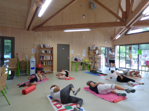People participate in a group exercise class on mats in a bright wooden room at Camping Seasonova La Forêt.