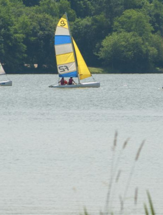 Veleros coloridos navegan en un lago tranquilo cerca de Sillé le Guillaume, en Pays de la Loire, Francia.