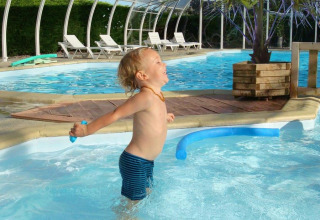Kleiner Junge spielt fröhlich im Pool im Camping Seasonova Le Point du Jour, Ferienpark in der Normandie, Frankreich.