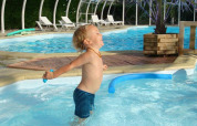 Kleiner Junge spielt fröhlich im Pool im Camping Seasonova Le Point du Jour, Ferienpark in der Normandie, Frankreich.