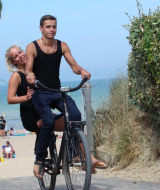 Una pareja joven anda en bicicleta junto a la playa en Camping Seasonova Le Point du Jour en Normandía, Francia.