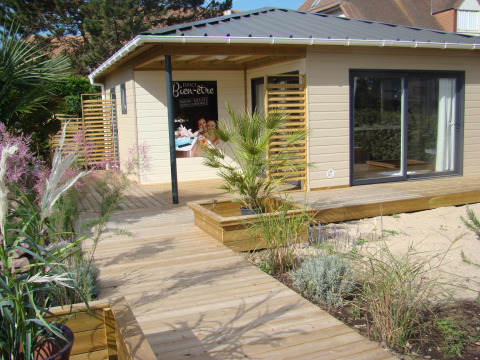 Terraza de madera y cabaña moderna con plantas en Camping Seasonova Le Point du Jour en Normandía, Francia.