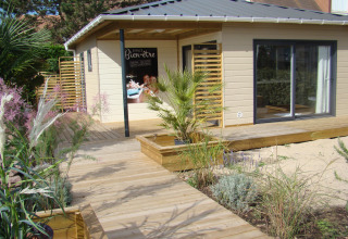 Wooden terrace and modern holiday cabin with garden plants at Camping Seasonova Le Point du Jour in Normandy, France.